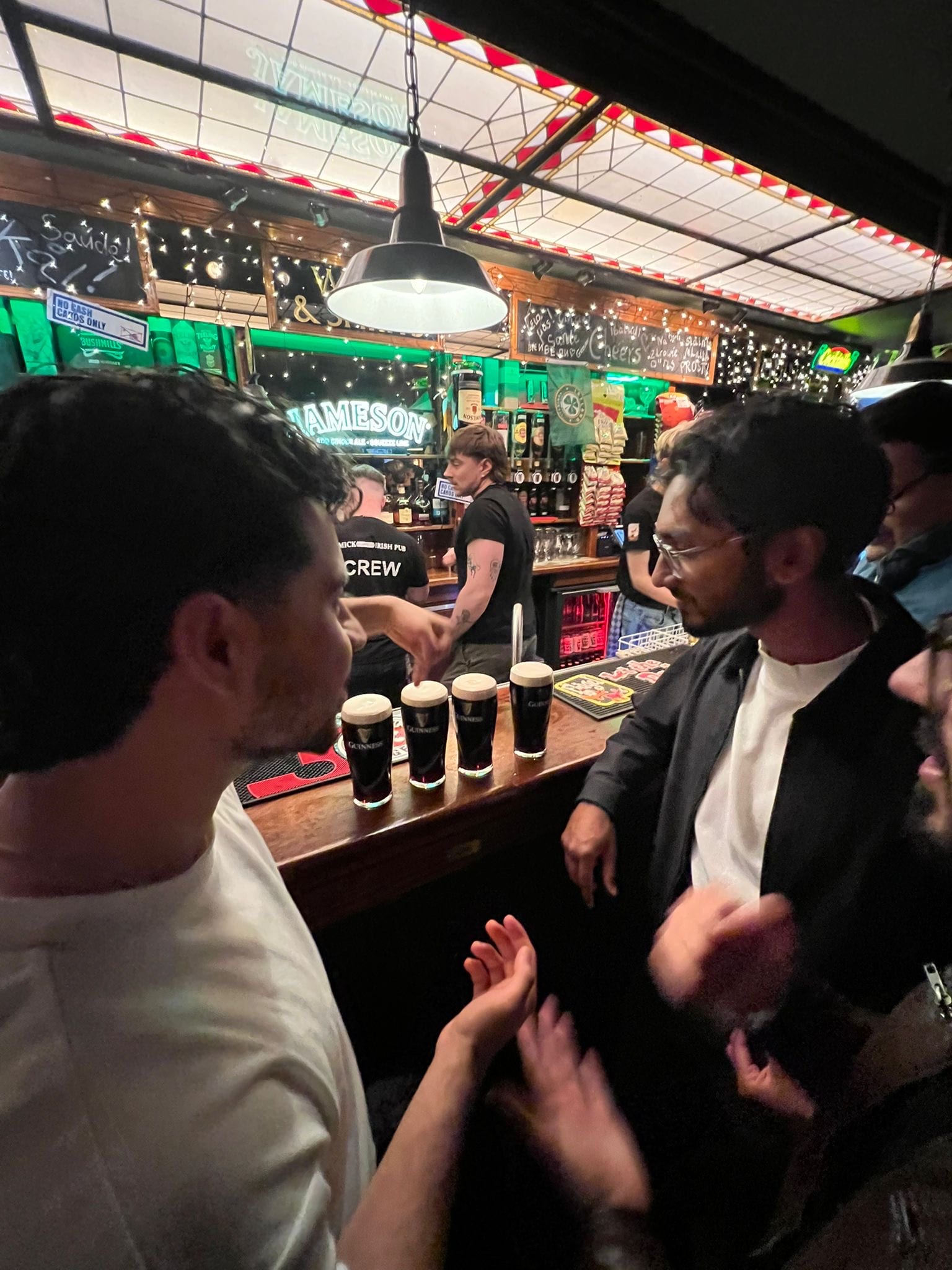 Mir and Bhuvan talking over pints of Guinness at a bar in Eindhoven